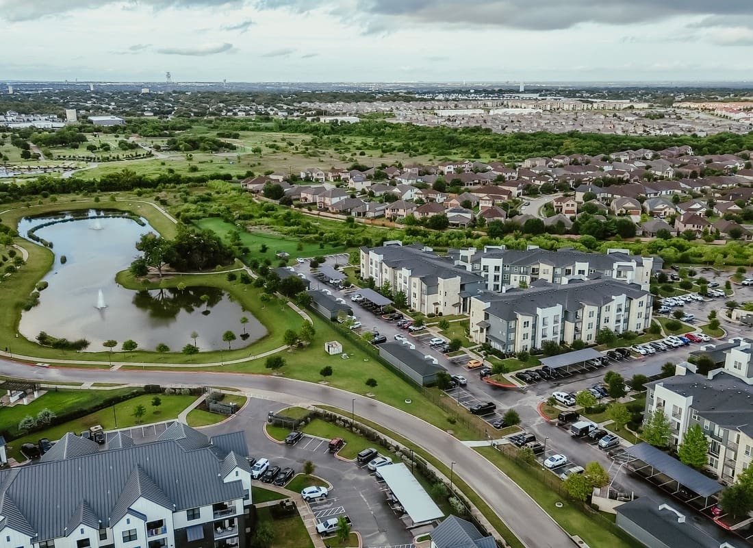Pflugerville, TX - Aerial View Of A Suburban Neighborhood With A Pond, Apartments, And Rooftop Homes